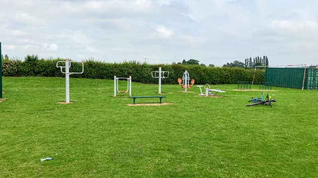 Outdoor fitness equipment on a grassy field, surrounded by hedges under a cloudy sky in Hambleton, Yorkshire.