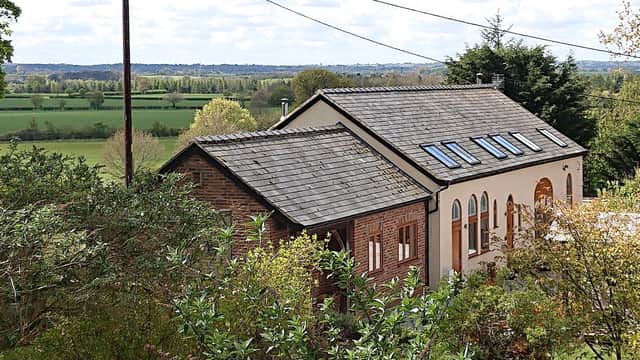 Glebe House holiday home with a sloped roof, surrounded by greenery and overlooking expansive fields in Hunsingore, Yorkshire.