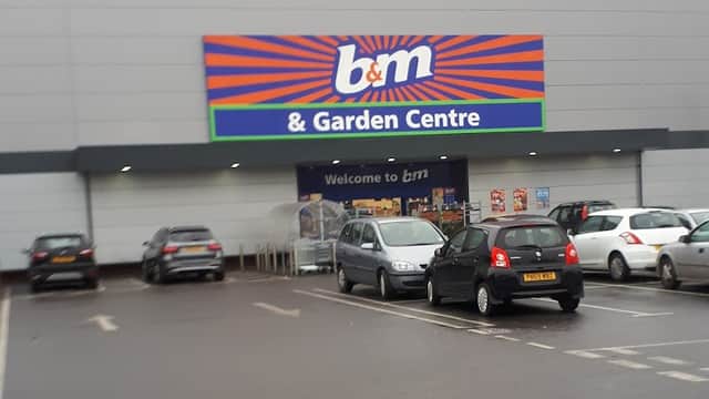 B&M & Garden Centre storefront with colorful signage and parked cars in a spacious retail park car park.