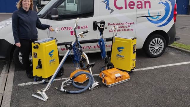 Woman standing beside a van with "Kerry Clean" logo, surrounded by cleaning equipment in a parking lot.
