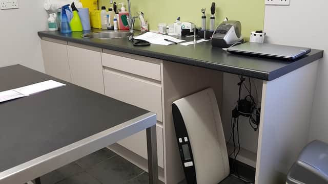 Veterinary practice workspace with cleaning supplies, a sink, paperwork, and a laptop on a counter.