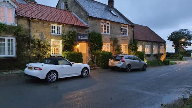Ellerby Residential Country Inn with two parked cars, surrounded by greenery and a quiet road in Hinderwell, Yorkshire.