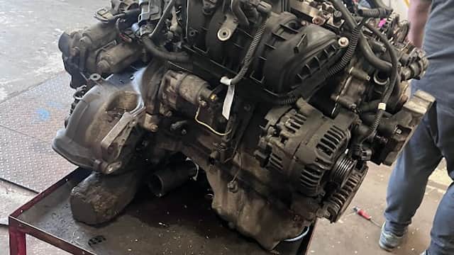 Engine on a workbench in a garage, with tools and equipment visible in the background.
