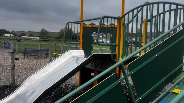 Playground equipment featuring a slide and climbing frame, set against a cloudy sky in Kirkheaton, Yorkshire.