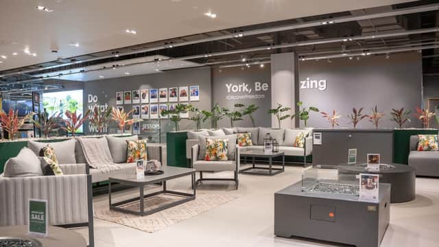 Modern garden furniture display featuring stylish sofas and tables, adorned with vibrant cushions and plants.
