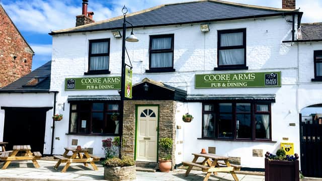 Coore Arms venue with a white facade, green signage, outdoor seating, and a welcoming entrance in Scruton, Yorkshire.