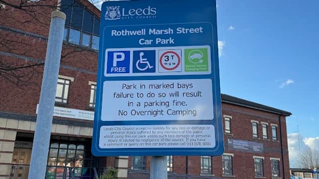 Rothwell Marsh Street Car Park sign with parking regulations, blue sky, and nearby brick building.