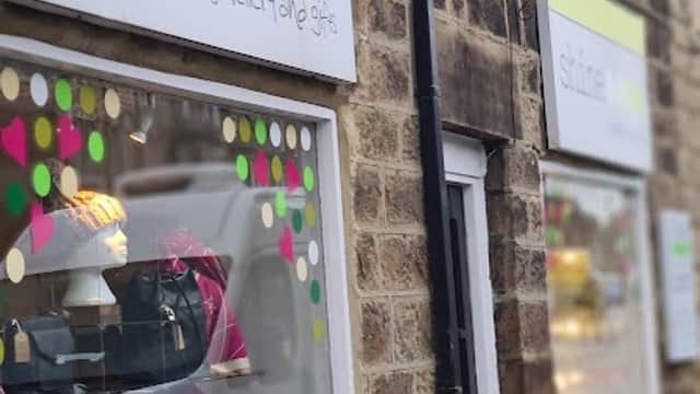 Jewellery shop "Shine" with colorful window displays, bags, and signs in a stone building in Harrogate, Yorkshire.