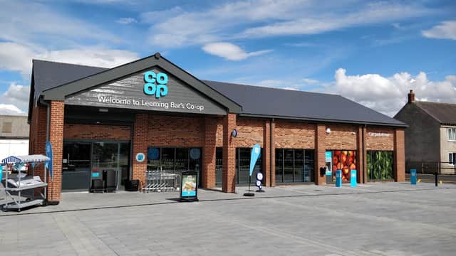 Modern brick grocery store with large windows, blue signage, and a paved entrance area in Leeming Bar, Yorkshire.