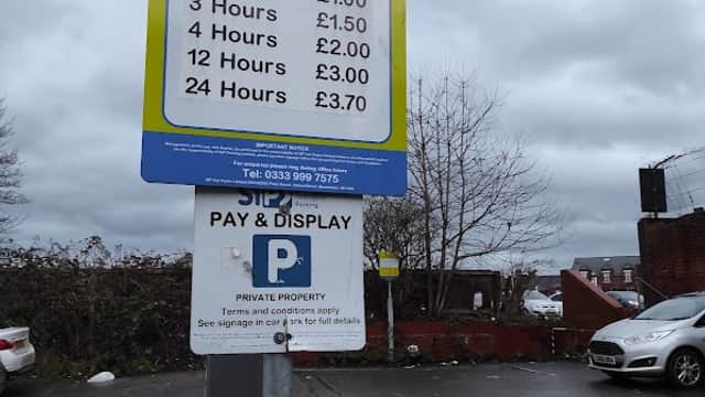 Parking sign detailing rates for various durations at Sagar parking in Castleford, with a car parked nearby.