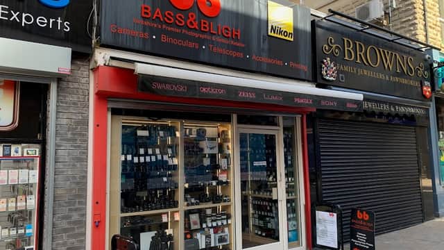 Storefront of Bass and Bligh, featuring cameras, binoculars, and telescopes, with prominent signage and display windows.