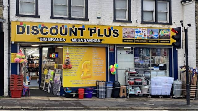 Bright storefront of Discount Plus featuring pet supplies, colorful signage, and various items displayed outside.