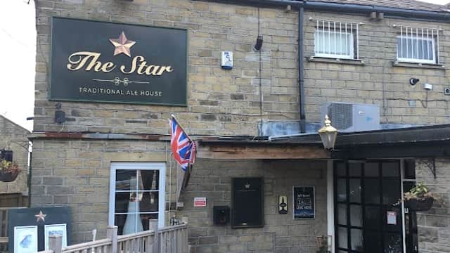 Traditional stone pub with a sign reading "The Star," British flag, and planters at the entrance in Lower Cumberworth.