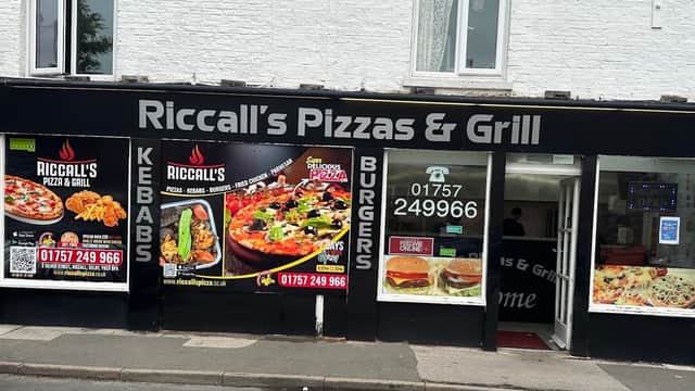 Signage for Riccall's Pizza & Grill featuring pizza, kebabs, and burgers, with contact details and colorful food images.