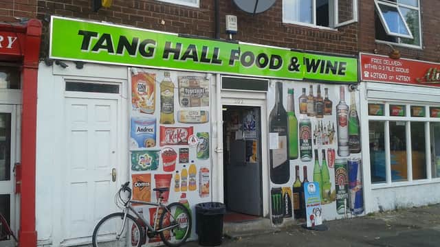 Bright storefront with "TANG HALL FOOD & WINE" sign, featuring beverage advertisements and a bicycle parked outside.