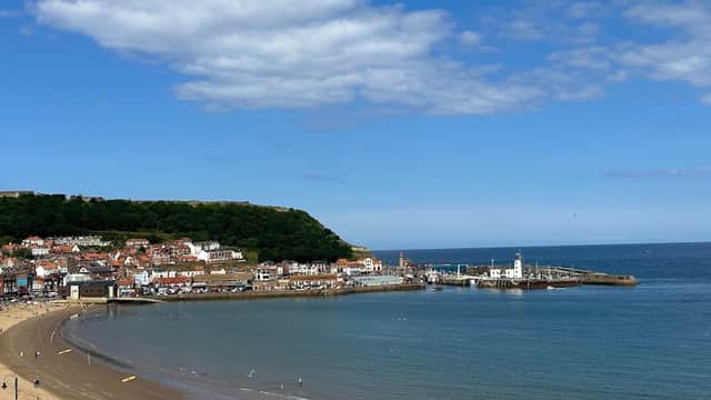Scarborough's South Bay with sandy beach, colorful buildings, and a pier under a clear blue sky.
