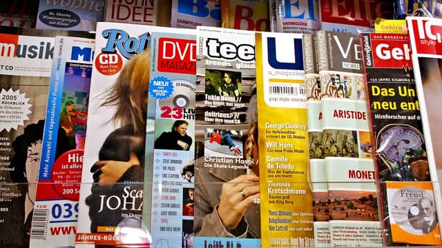 Magazines displayed on shelves, featuring various titles and colorful covers in a retail setting.