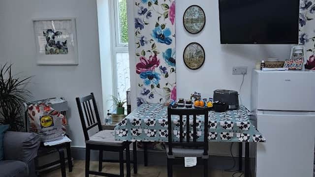 Cozy interior of East Cowton Village Hall featuring a dining table, chairs, fridge, and floral decor.