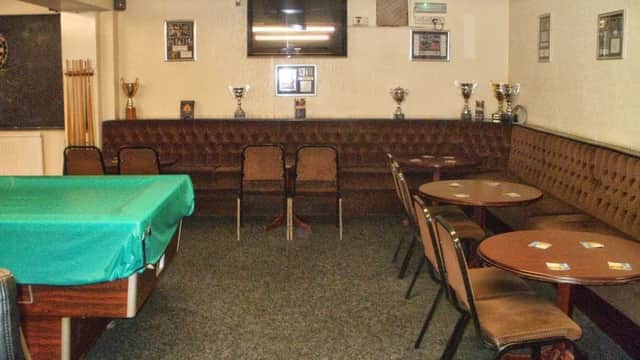 Interior of Park Social Club with a green pool table, brown seating, tables, trophies, and a wall-mounted TV.