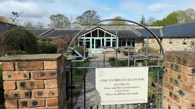 Gate with a sign reading "Strictly Private Access" leading to a courtyard with tables and chairs, surrounded by stone buildings.