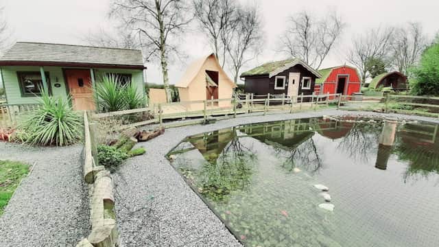 Glamping cabins and a pond surrounded by gravel paths and greenery at Seaways Glamping and Camping in Yorkshire.
