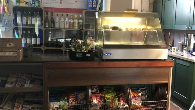 Counter with a glass display case, snacks, drinks, and a variety of magazines in a cozy post office setting.