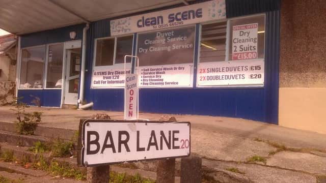 "Clean Scene storefront with signs for duvet cleaning services and a 'Bar Lane' street sign in front."