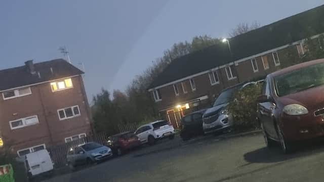 Car park with parked vehicles, residential buildings in the background, and a dusky sky in Woodhouse, Yorkshire.