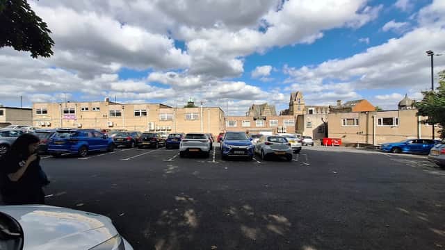 Free parking lot at Lidget Hill, surrounded by buildings and a partly cloudy sky in Pudsey, Yorkshire.