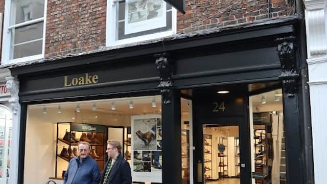Loake Shoemakers storefront in York, with two men standing outside and a brick facade featuring large windows.