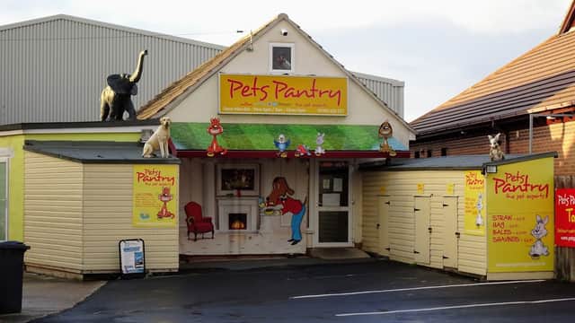 Colorful storefront of Pets Pantry with pet-themed decorations and signage, featuring animals and bright colors.