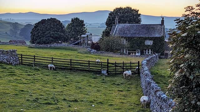 Lindon Guest House in a scenic Yorkshire landscape, with sheep grazing and hills in the background at sunset.