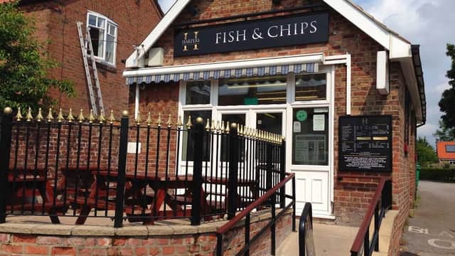 Brick restaurant exterior with a sign reading "Fish & Chips," outdoor seating, and a blue awning in Wetwang, Yorkshire.