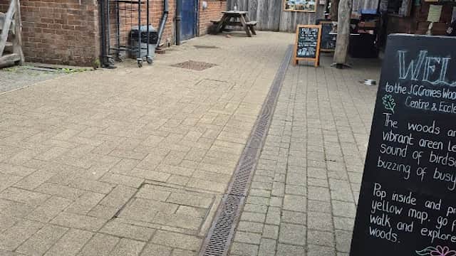 Pathway leading to the Ecclesall Woods Visitor Centre with wooden buildings and a chalkboard sign.