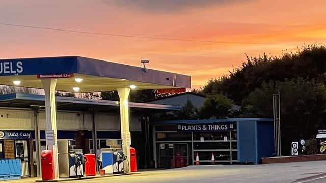 JB Fuels petrol station at dusk, featuring fuel pumps and a sign for "Plants & Things" with a colorful sunset backdrop.