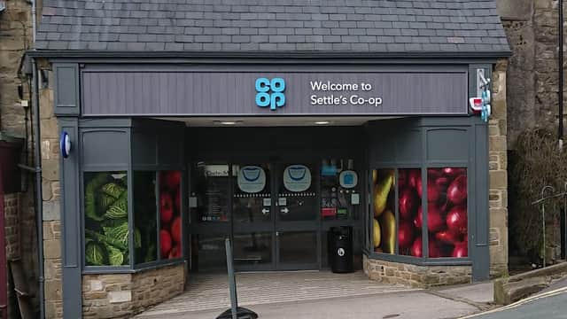 Entrance to Settle Co-op with colorful fruit and vegetable displays on windows, located in Market Square, Yorkshire.