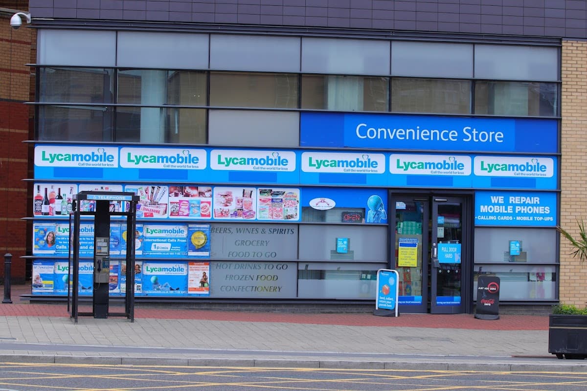 Convenience store exterior featuring signs for Lycamobile, mobile repair services, and various grocery items.