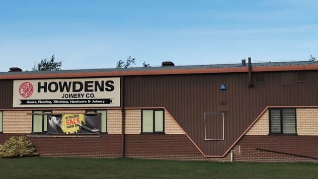 Howdens Joinery Co. building with signage, featuring a brick facade and a clear blue sky.