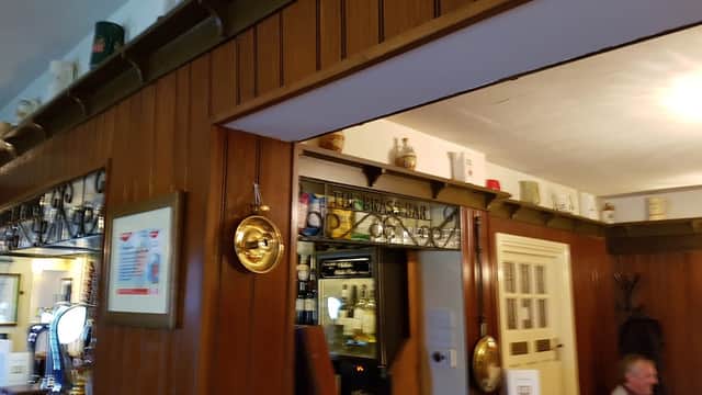 Wood-paneled interior of St Vincent Arms restaurant, featuring a bar area and decorative plates on the ledge.