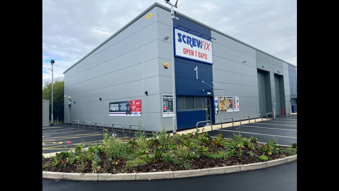 Screwfix store exterior with signage, parking lot, and landscaped area in front, located in Monks Cross, York.