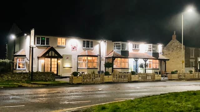 The Cayley Arms pub illuminated at night, featuring a welcoming facade and surrounding greenery in Ebberston, Yorkshire.