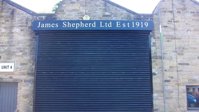 Black roller shutter with "James Shepherd Ltd Est1919" sign on a stone building in Hebden Bridge, Yorkshire.