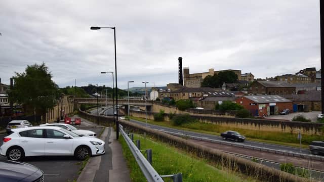 Pay & Display car park with parked cars, green grass, and a view of buildings and a road in Bingley, Yorkshire.