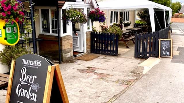 The Black Swan Overton bar entrance with hanging flowers, a beer garden sign, and a canopy outside.