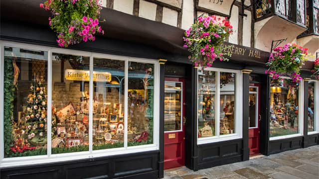 Charming gift shop with festive window displays, colorful flower baskets, and traditional architecture in York, Yorkshire.