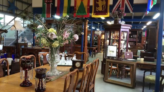 Antique shop interior with wooden furniture, decorative vases, and various flags hanging from the ceiling.