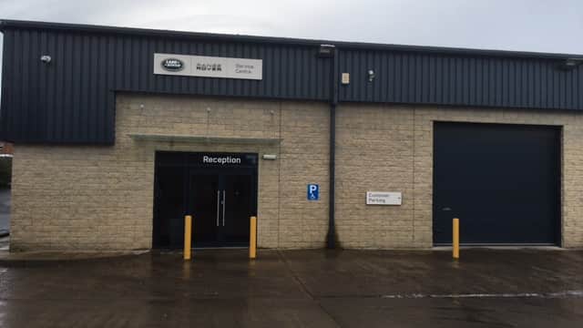 Lloyd Land Rover Leyburn Service Centre with a reception entrance and large garage door, set in a stone building.