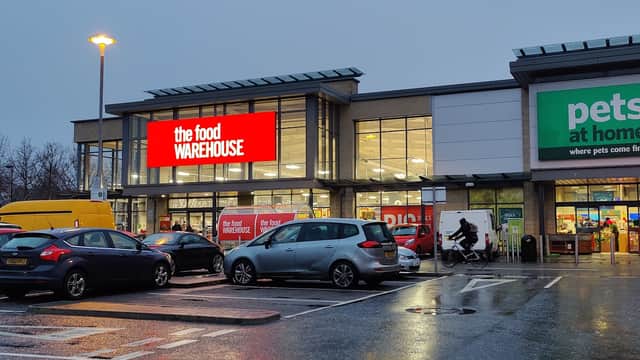The Food Warehouse storefront with bright signage, parking lot filled with cars, and Pets at Home next door.