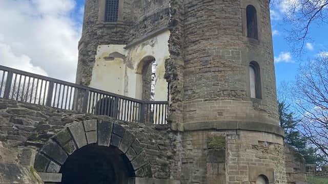 Ruins of Stainborough Castle with stone towers and archways, set against a blue sky with scattered clouds.