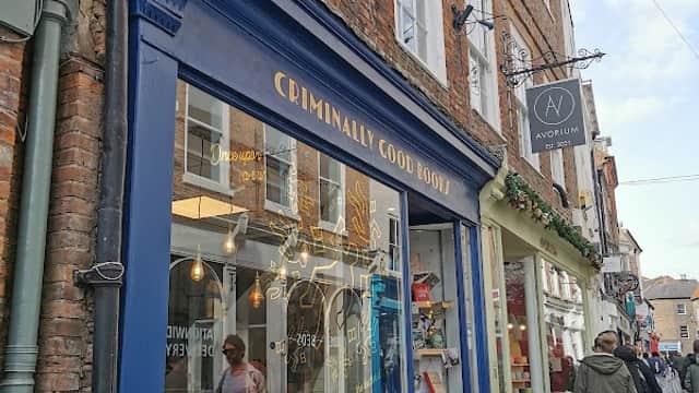 "Exterior of 'Criminally Good Books' shop in York, featuring colorful book displays and a charming brick facade."